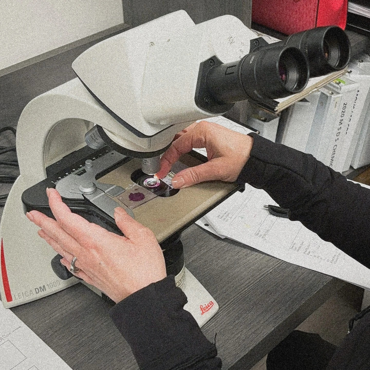 Dermatologist operating a Leica microscope to examine skin samples during a diagnostic procedure